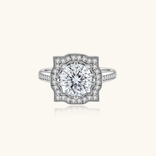 Sterling silver ring with round moissanite center stone in ornate scalloped halo setting on white background.