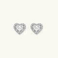 Close-up of heart-shaped moissanite stud earrings in sterling silver halo setting on cream background.