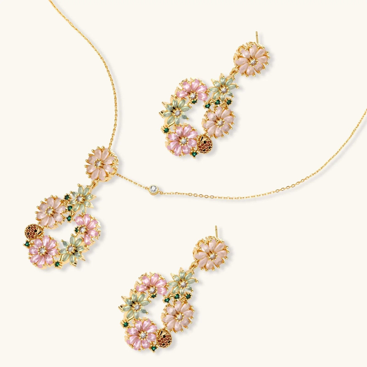 Havora floral jewellery set featuring a gold-tone necklace and drop earrings with pink, green petals and ladybirds.