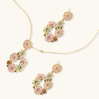 Havora floral jewellery set featuring a gold-tone necklace and drop earrings with pink, green petals and ladybirds.